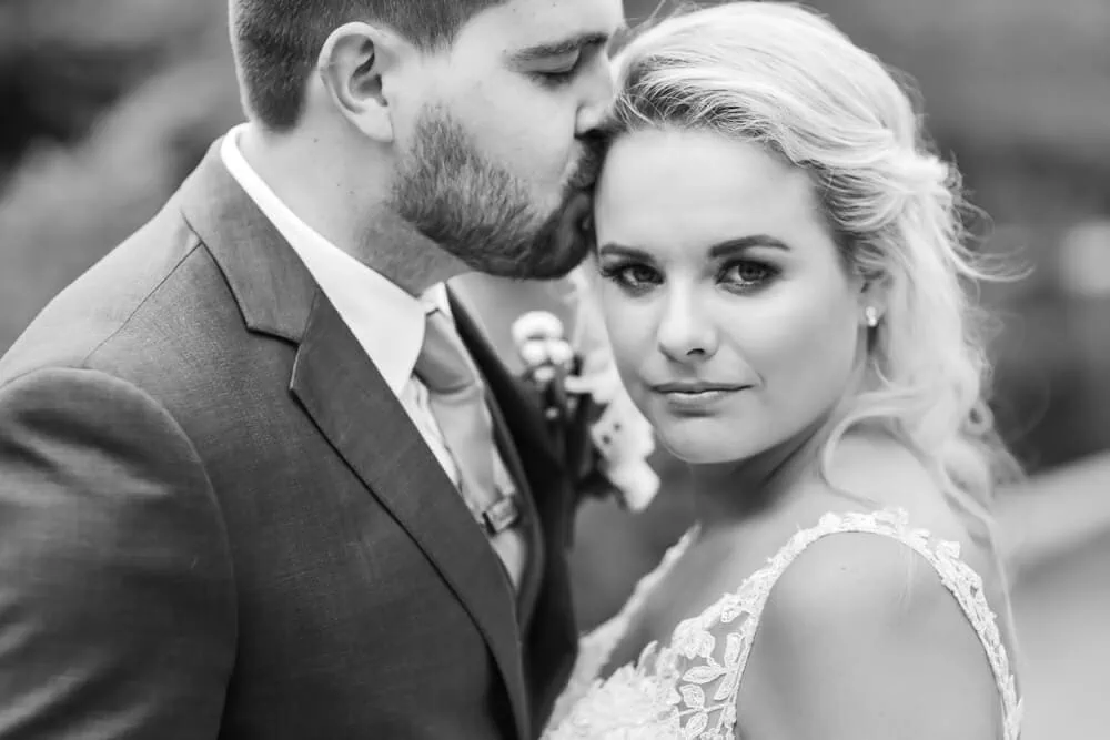 groom kissing blonde bride temple smouldering bw