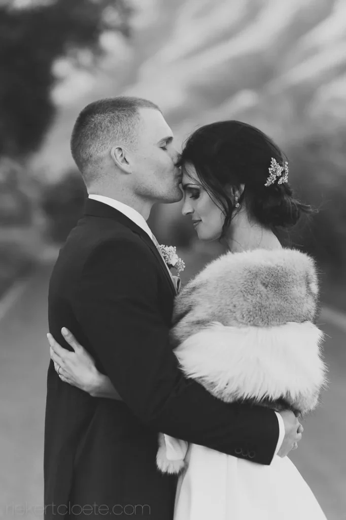 groom kissing bride temple winelands driveway bw