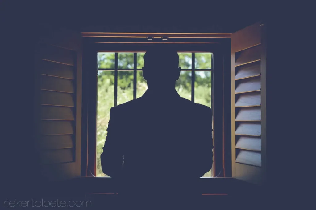 groom silhouette window shutters getting ready