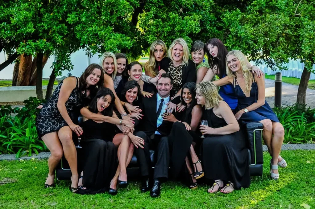 groom surrounded female guests garden group photo