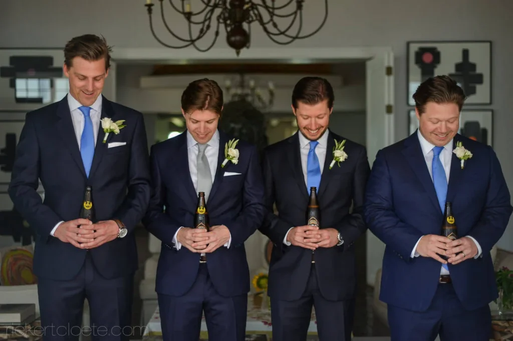 groomsmen navy suits holding beers indoors