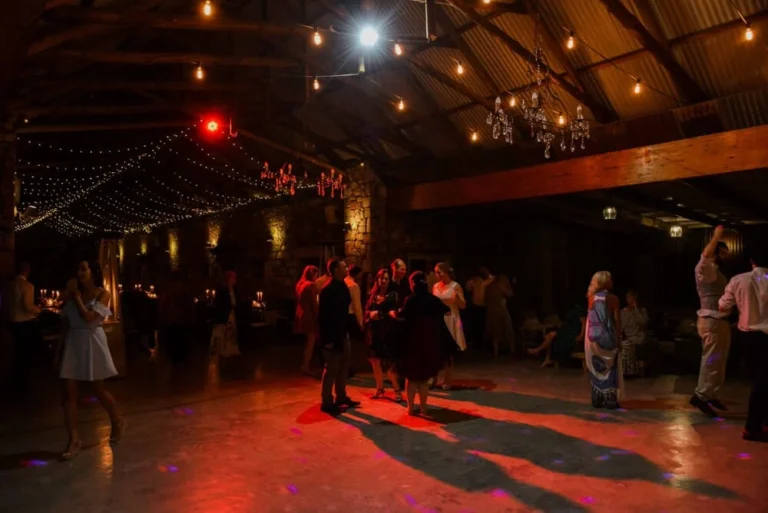 guests dancing rustic barn fairy lights red glow