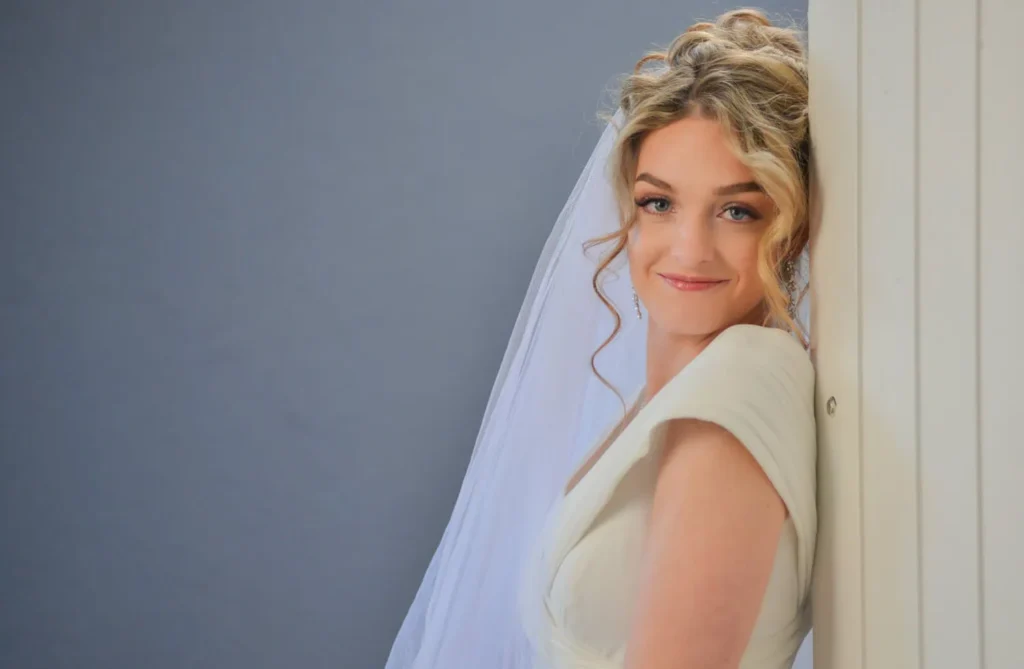 smiling bride veil updo leaning door portrait
