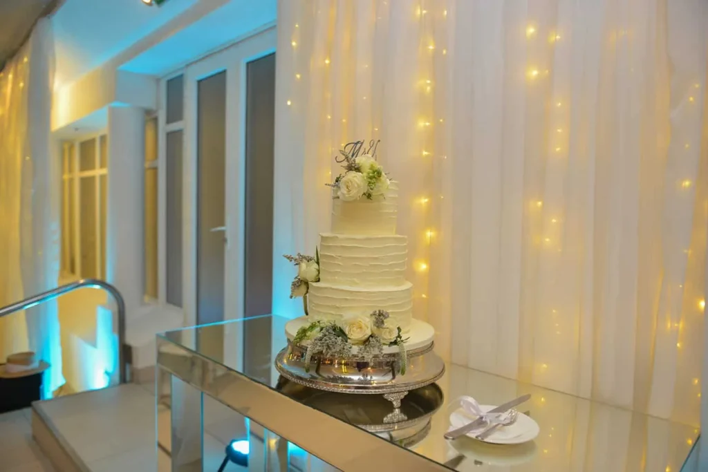 three tier textured cake white roses fairy lights
