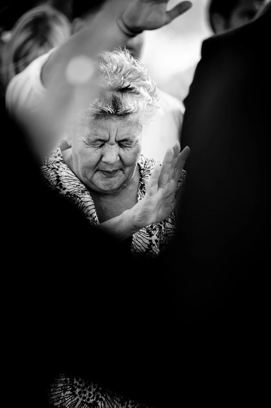 wedding guest praying hands raised outdoor ceremony