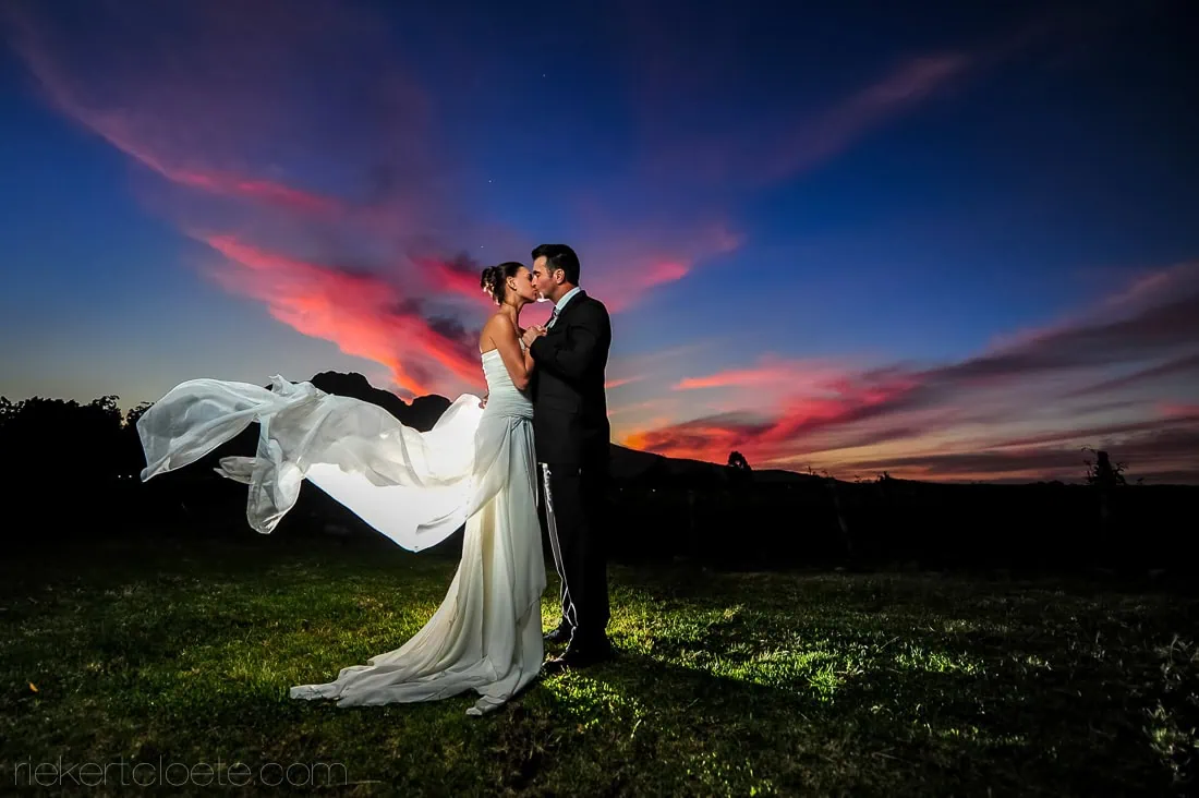 Couple kissing veil blowing red sunset – Allée Bleue, Franschhoek
