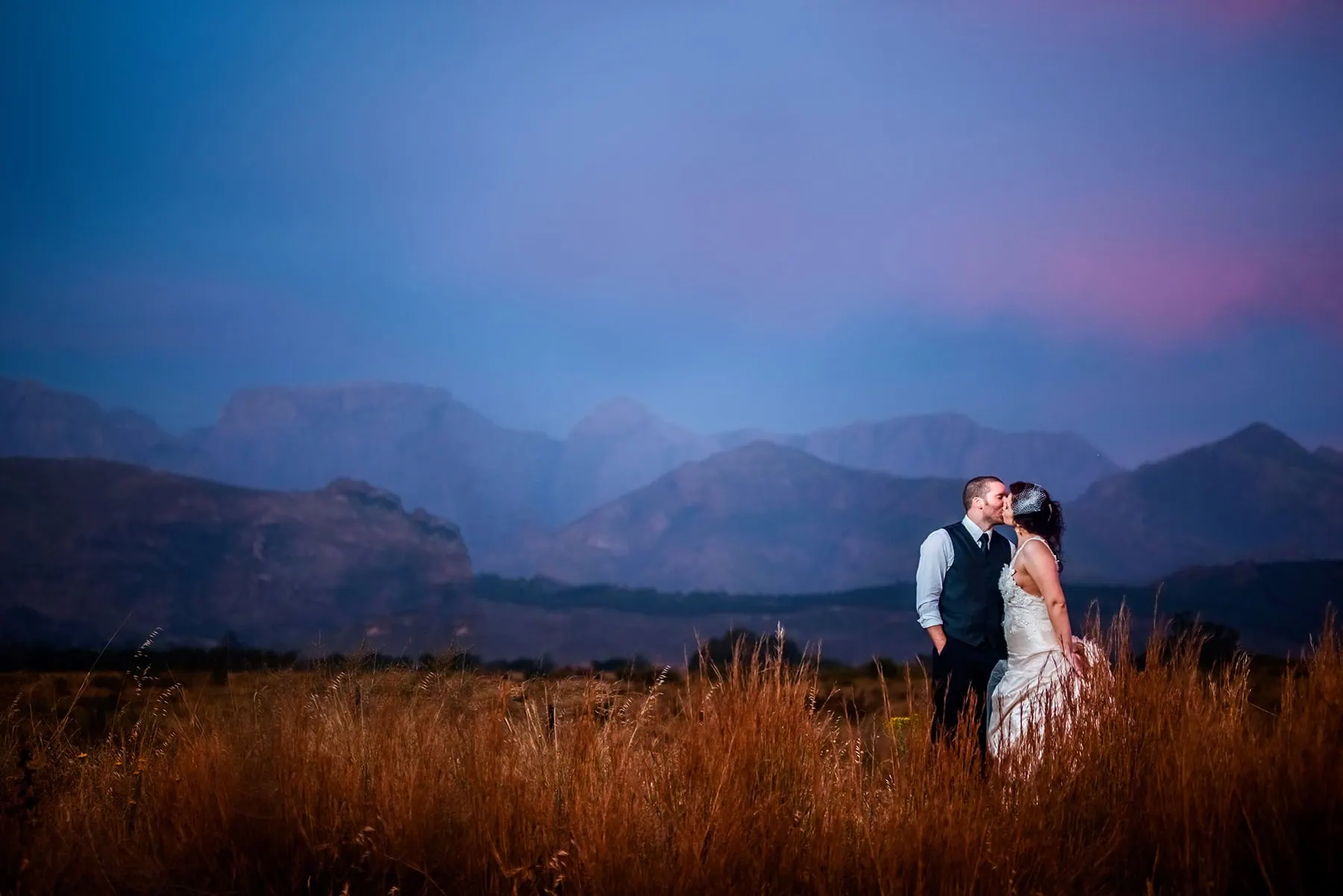 Couple kissing wheat field dramatic blue mountains – Simondium Country Lodge, Paarl