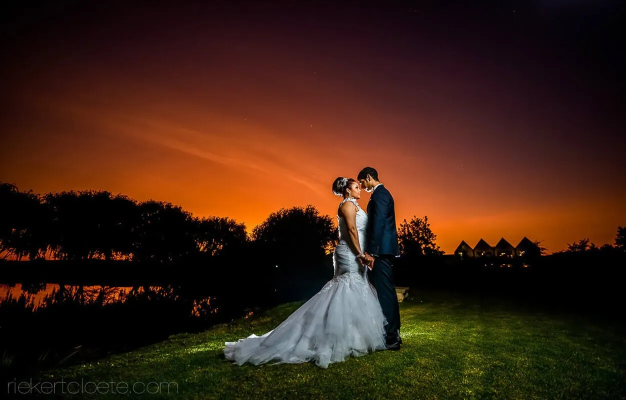 Couple kiss glowing red orange sunset venue lawn – Vredenheim, Stellenbosch